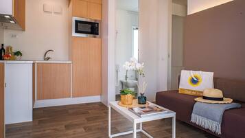 Ein kompakter Wohnraum mit einer Küchenzeile, einem Essbereich und einer Sitzecke inklusive Sofa und kleinem Tisch.