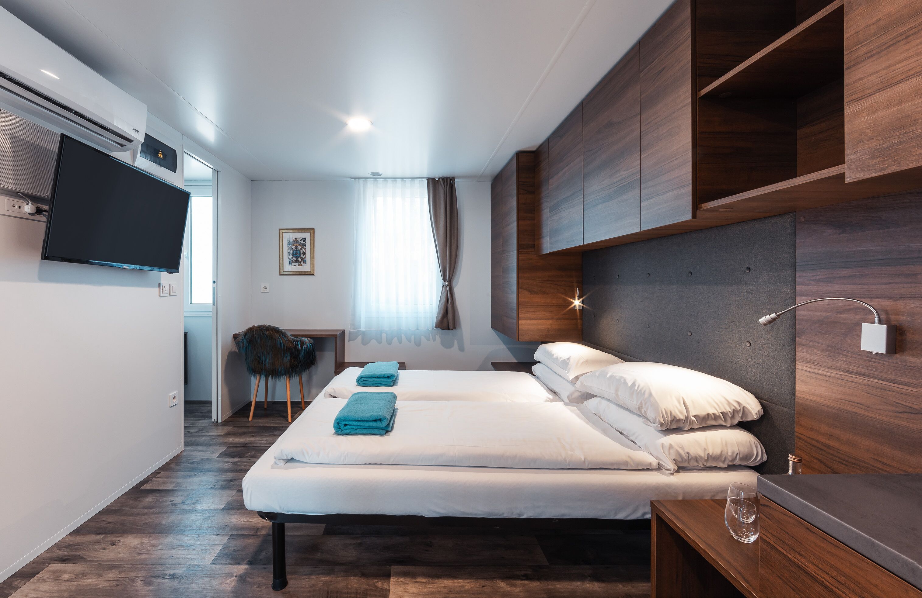 A modern hotel room with a large bed, a desk, and a television.