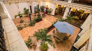 A spacious atrium with a central seating area, surrounded by potted plants and a red vending machine. - Gran Hotel de Merida (Mérida)