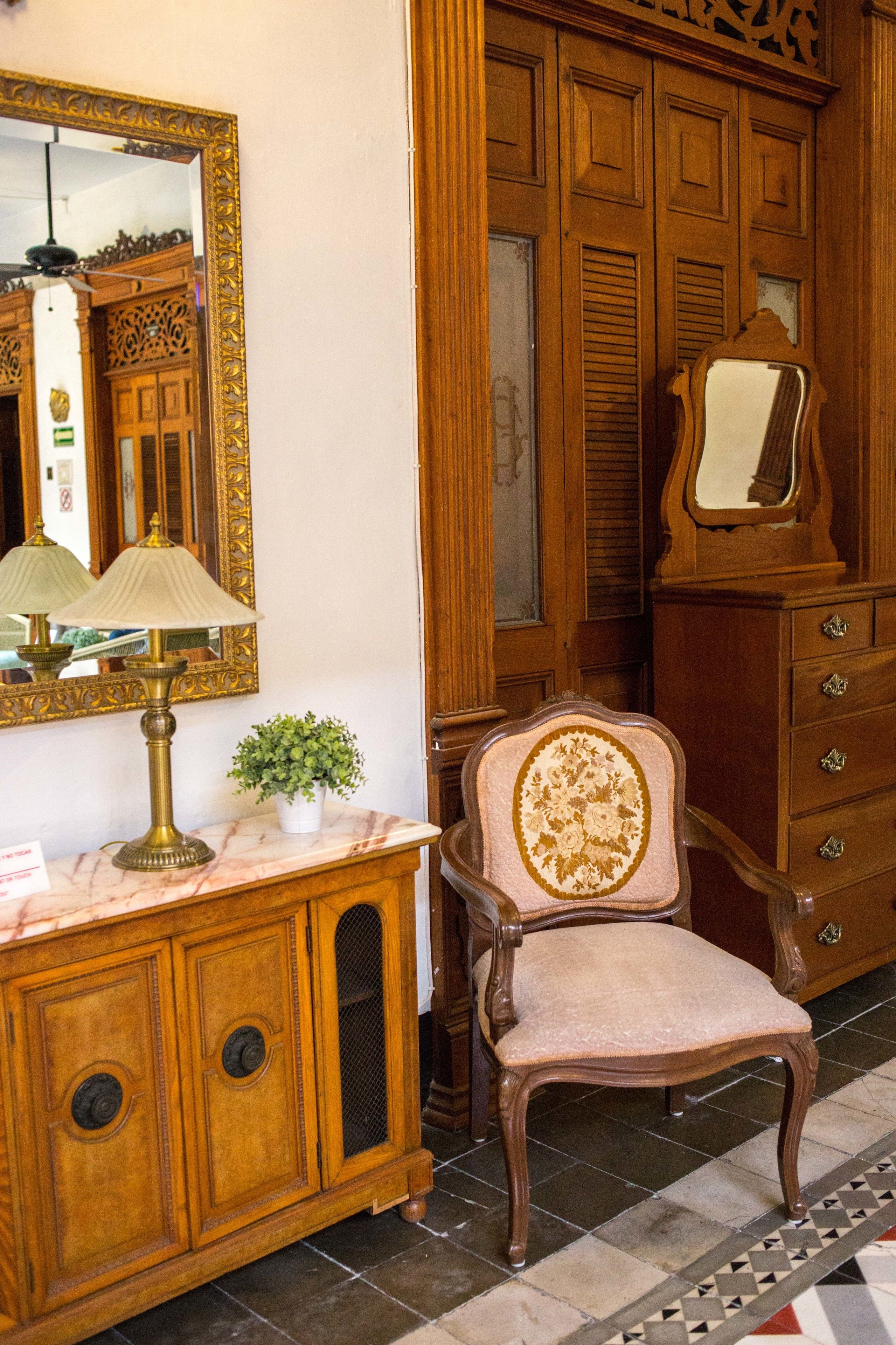 A wooden dresser with a mirror, a lamp, and a chair.