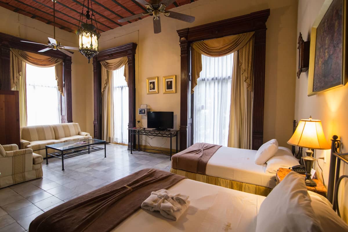 Habitación de hotel con dos camas, un sofá, un televisor y un escritorio.