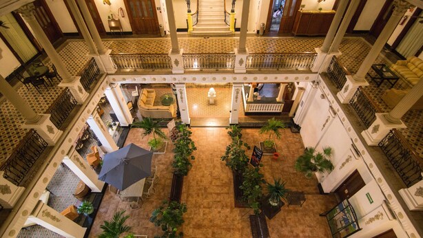 A spacious atrium with a central staircase, multiple balconies, and a variety of seating areas. - Gran Hotel de Merida (Mérida)