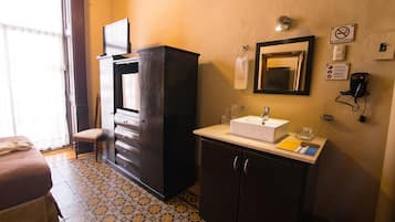 A hotel room with a bed, a dresser, a mirror, a sink, and a telephone.