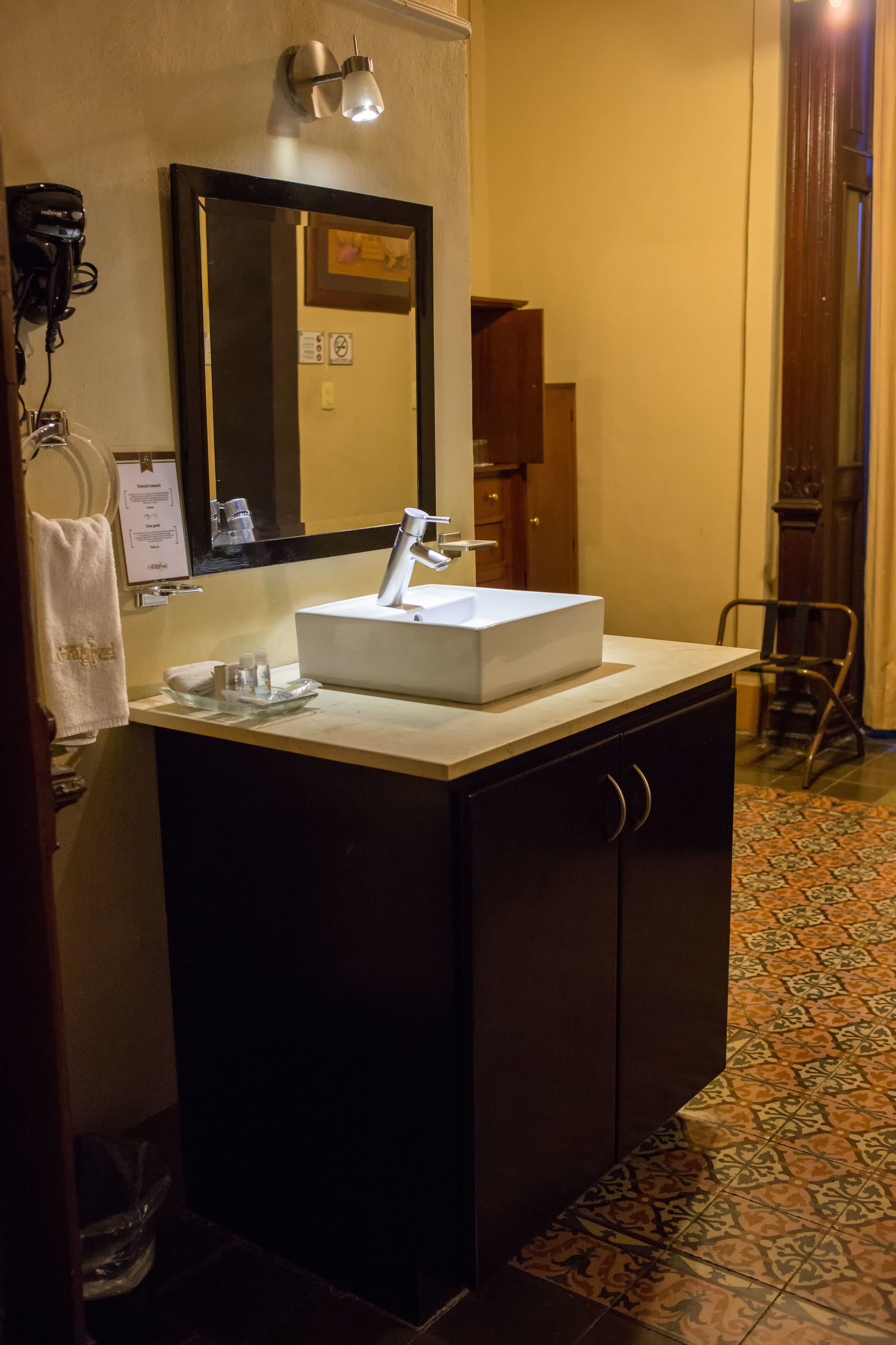 A bathroom with a white sink, dark cabinets, a mirror, and a towel rack.