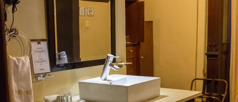 A bathroom with a white sink, dark cabinets, a mirror, and a towel rack.
