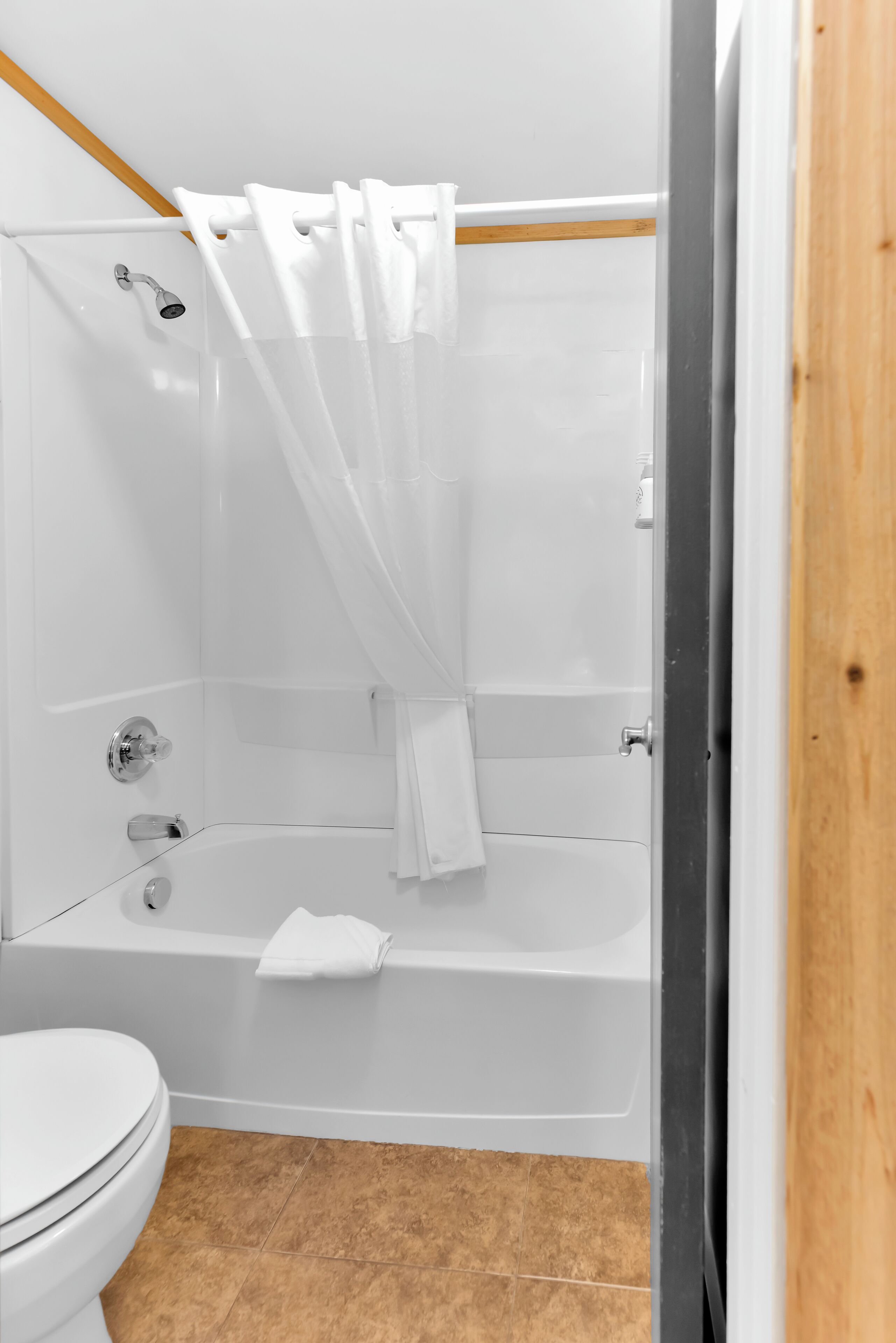 A bathroom with a white bathtub, a shower, and a toilet.