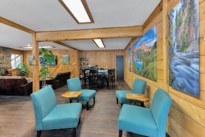 A wooden interior with seating, a table, and a painting of a mountain landscape.