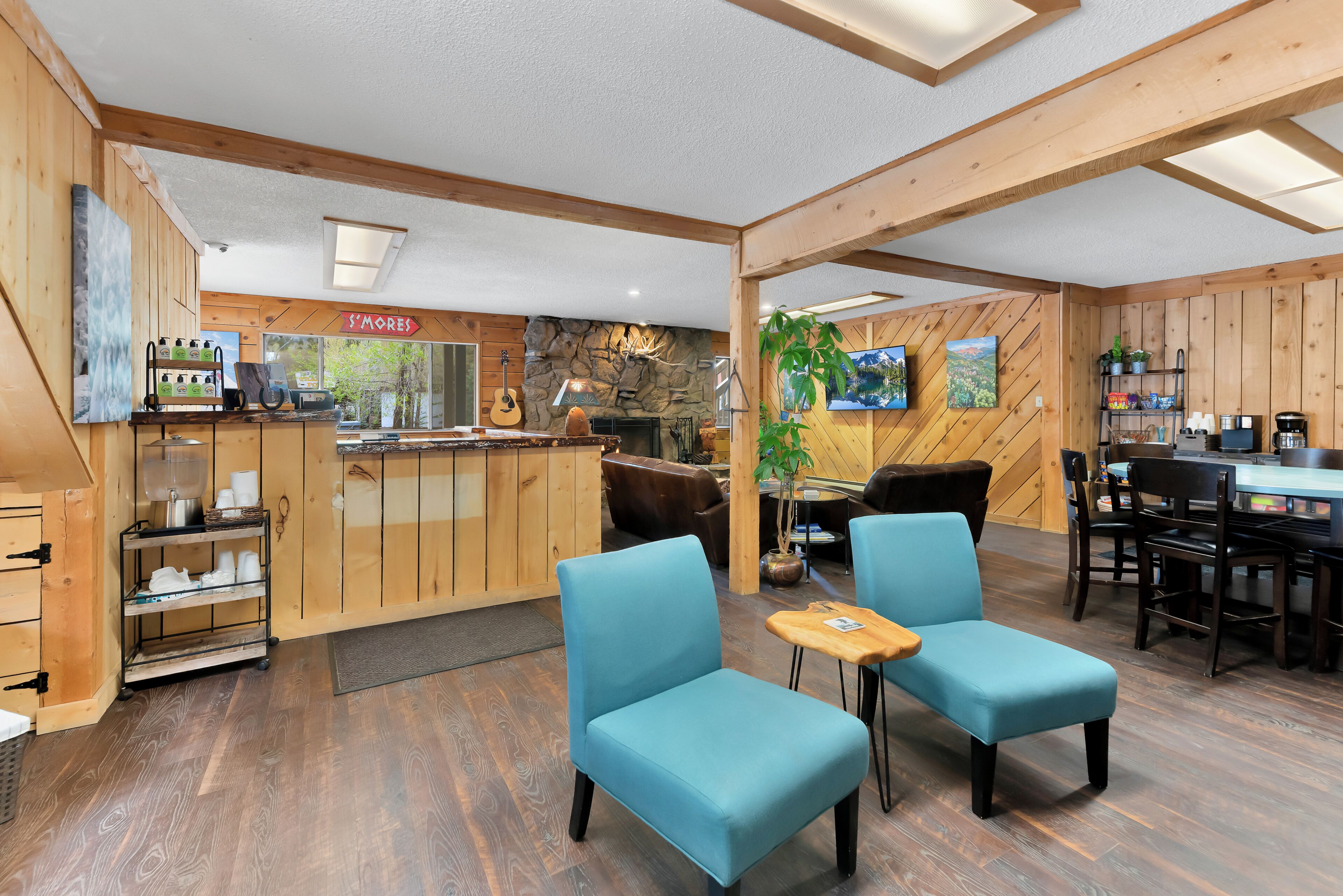 A cozy interior with wooden walls, a stone fireplace, a bar area, and blue seating.