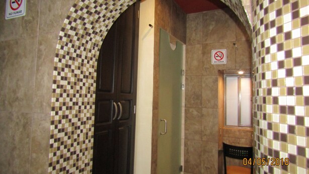 An arched doorway with checkered mosaic tiles, a dark wooden door, and a green wall. - Hotel 1973 (San Luis Potosi)