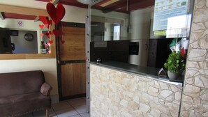 A reception area with a stone wall, a wooden door, and a brown sofa. - Hotel 1973 (San Luis Potosi)