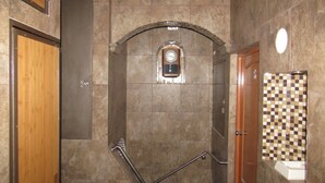 A bathroom with a tiled floor, a wooden door, a clock, and a checkered tile backsplash. - Hotel 1973 (San Luis Potosi)