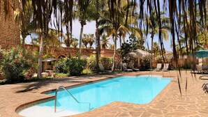 Una piscina con sillas de descanso y palmeras.