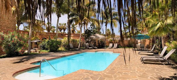 A swimming pool with lounge chairs and palm trees.