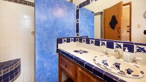 A bathroom with a blue and white tiled wall, a wooden vanity, and a mirror. - Posada del Molino (Todos Santos)