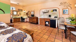Una habitación amplia con una cama grande, una kitchenette, un comedor y un baño.