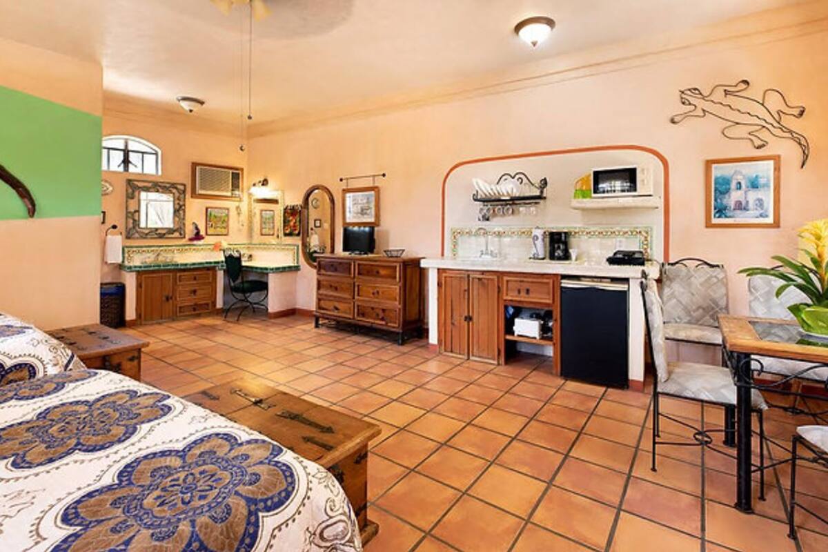 A spacious room with a large bed, a kitchenette, a dining area, and a bathroom.
