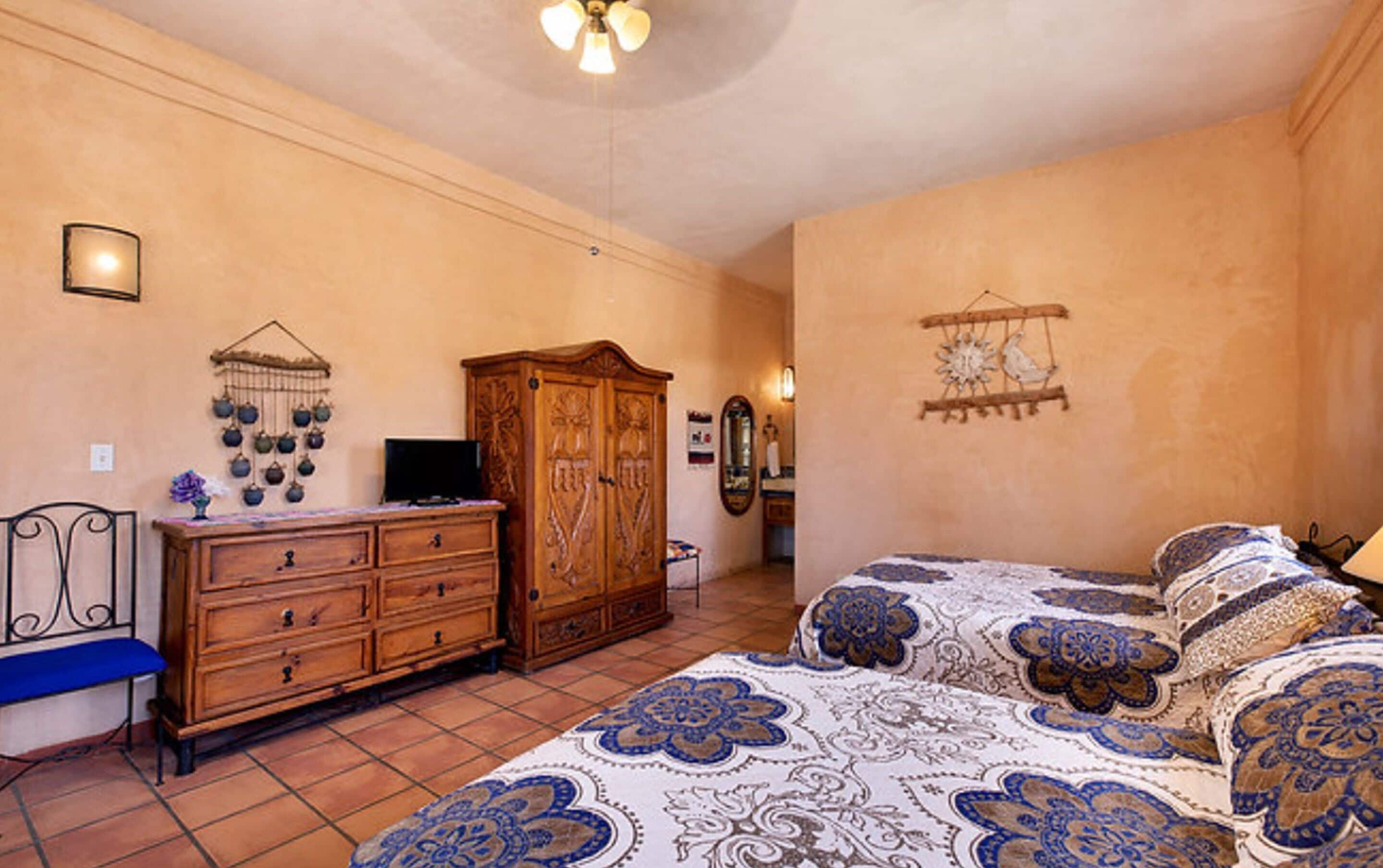 Een slaapkamer met een bed, een houten dressoir en een televisie.