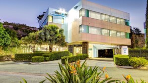 A modern hotel with a two-story structure, a well-maintained garden, and a clear sky. - Springfield Lakes Boutique Hotel (Springfield Lakes)