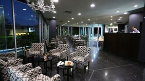 A modern lounge area with patterned seating, a bar, and a view of the outdoors. - Springfield Lakes Boutique Hotel (Springfield Lakes)