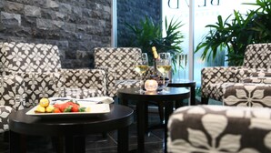 A seating area with patterned sofas, a small table with a fruit platter, and two glasses of white wine. - Springfield Lakes Boutique Hotel (Springfield Lakes)