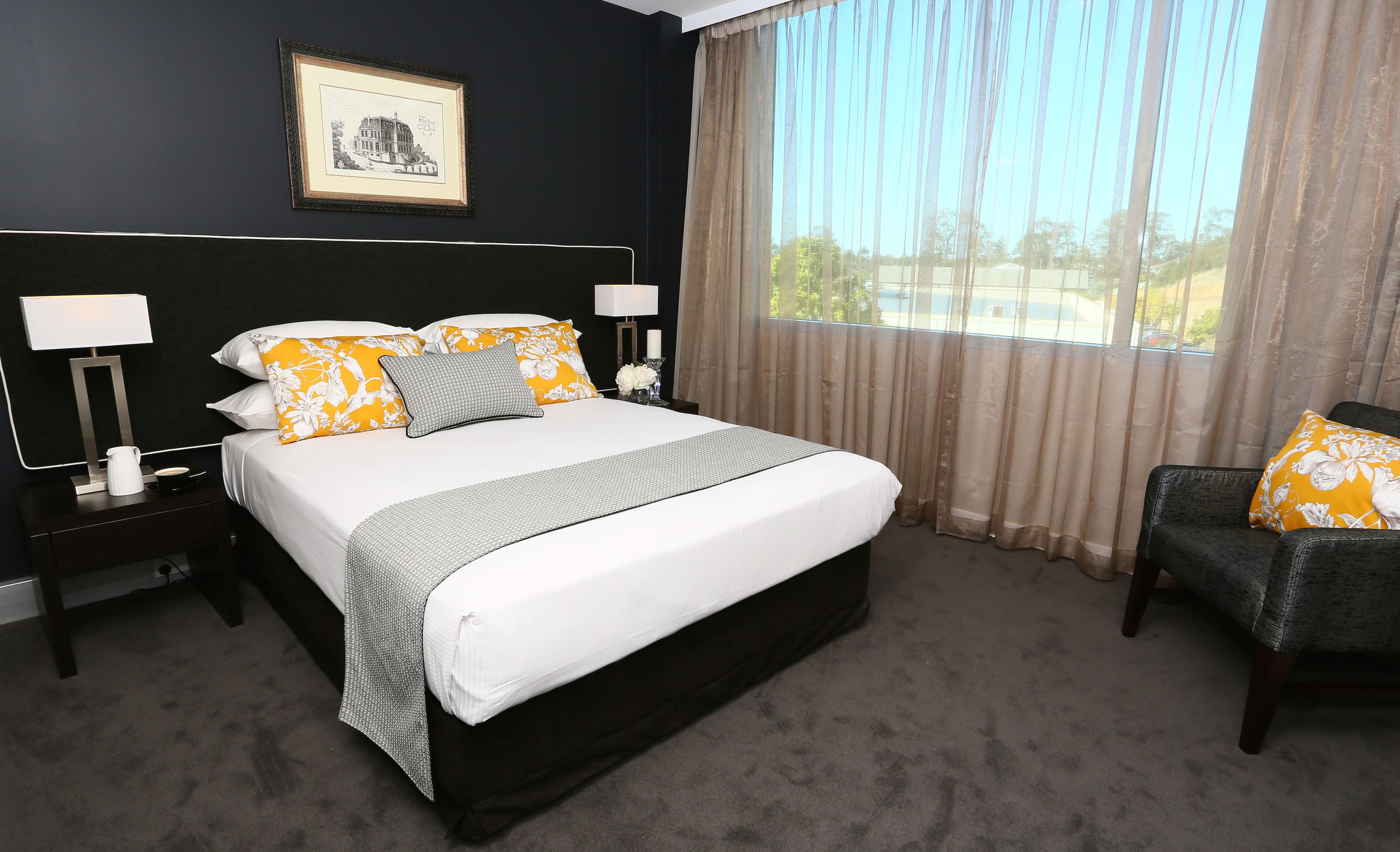 A neatly arranged hotel room with a large bed, two bedside tables, a chair, and a window with curtains.