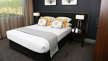 Una cama bien hecha con sábanas blancas, dos lámparas de noche y almohadas decorativas.