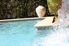 A clear pool with a large vase and a water feature.