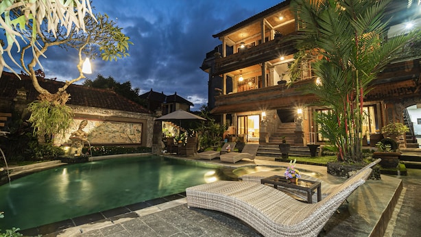 A two-story building with a swimming pool, outdoor seating, and a well-lit entrance. - Kun - Kun Guest House Ubud (Ubud)