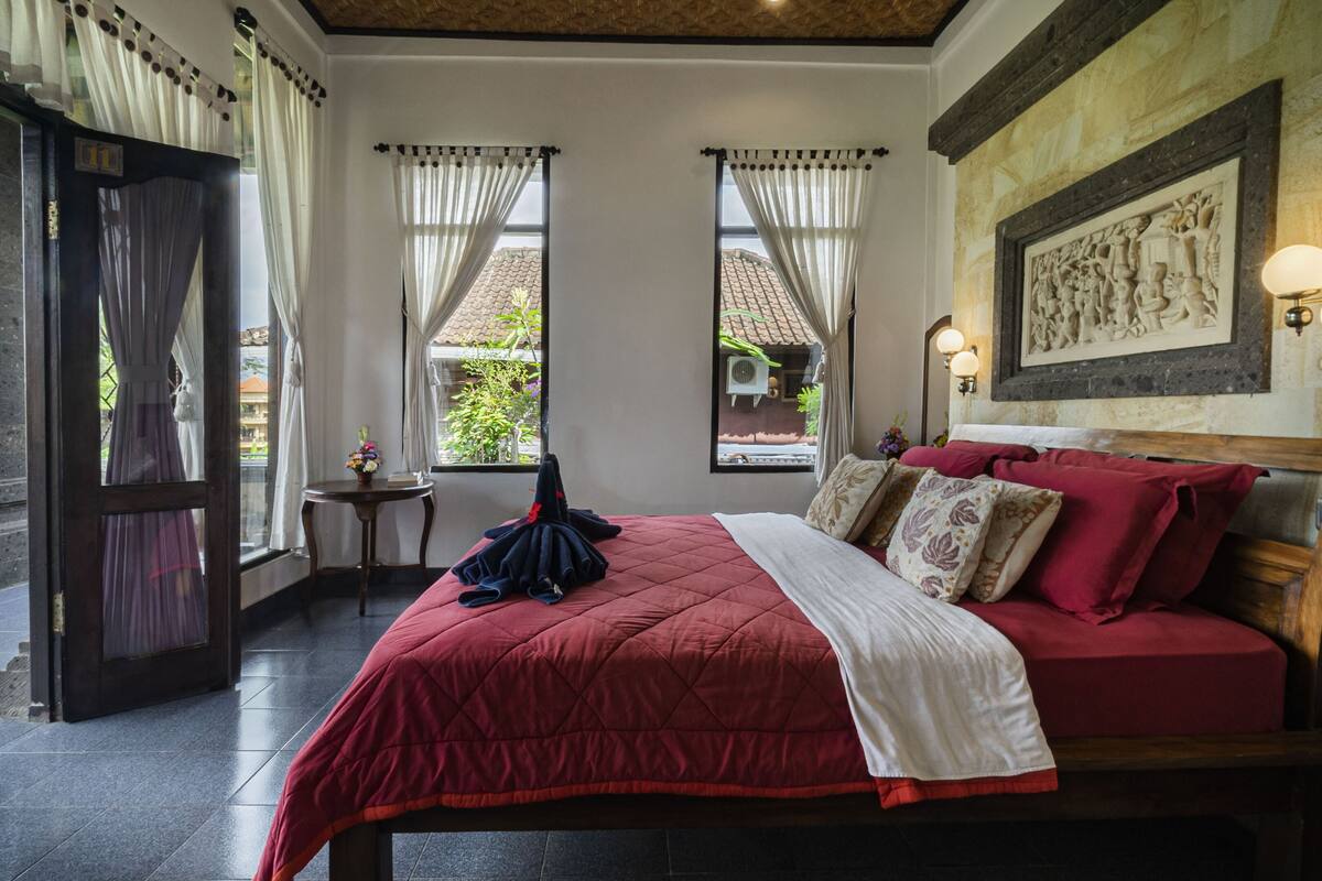 A room with a bed, a small table, and a window with curtains.