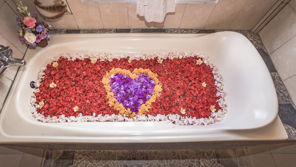 A bathtub filled with rose petals arranged in a heart shape. - Kun - Kun Guest House Ubud (Ubud)
