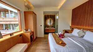 A modern bedroom with a wooden bed, a bedside table, a built-in wardrobe, and a bathroom with a round mirror and sink. - Kun - Kun Guest House Ubud (Ubud)