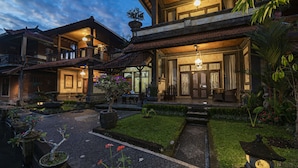 A traditional building with a covered porch, a garden with a koi pond, and a well-maintained lawn. - Kun - Kun Guest House Ubud (Ubud)