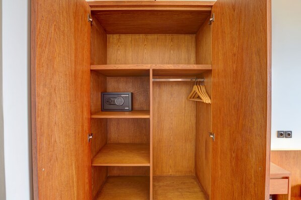 A wooden wardrobe with multiple shelves and hanging space. - Kun - Kun Guest House Ubud (Ubud)