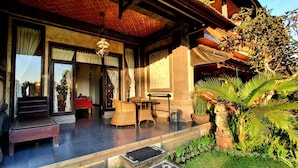 A covered outdoor area with a bench, wicker furniture, and potted plants. - Kun - Kun Guest House Ubud (Ubud)