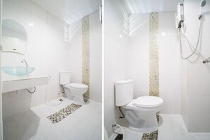 A bathroom with a glass sink, toilet, and shower.