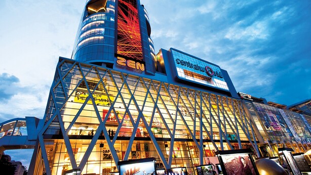 A modern hotel with a prominent glass facade, a central atrium, and a distinctive tower structure. - OYO 437 Hostel Na Nara (Bangkok)