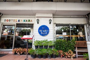 A storefront with a sign reading "ZOSTELNARA" and a blue circular sign with Thai script.