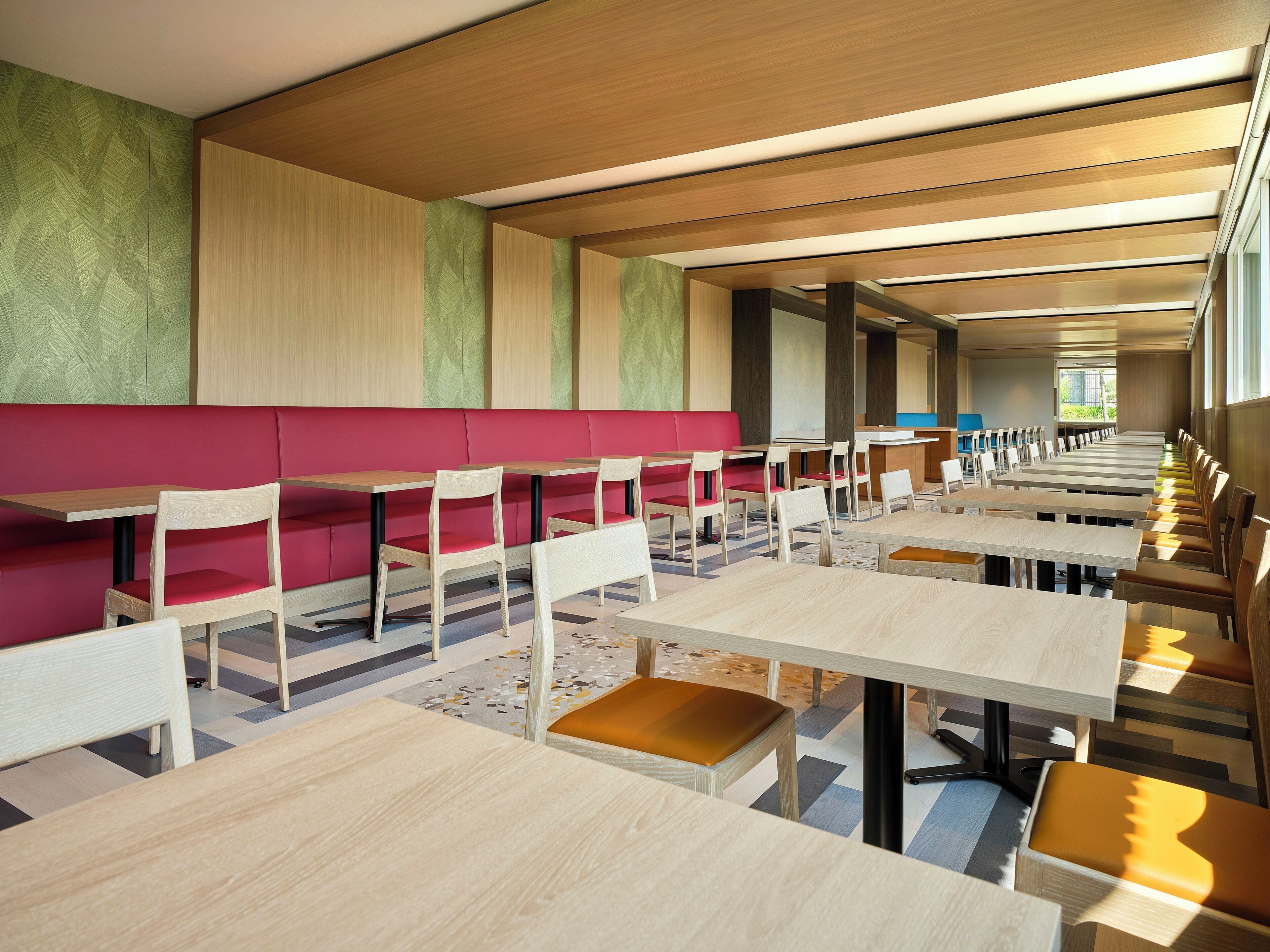 A modern dining area with booths and tables, wooden ceiling, and patterned walls.