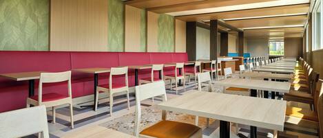 A modern dining area with booths and tables, wooden ceiling, and patterned walls.