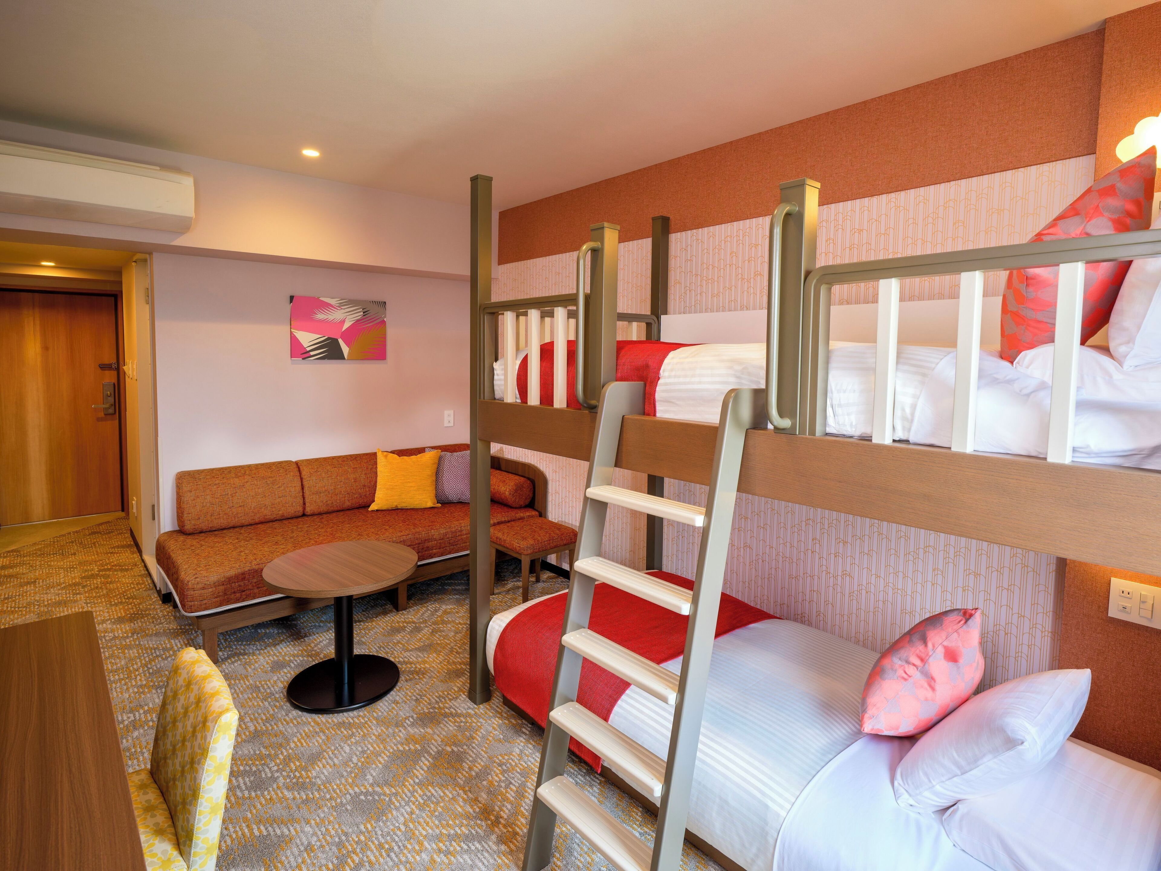 A hotel room with bunk beds, a sofa, a small round table, and a patterned carpet.