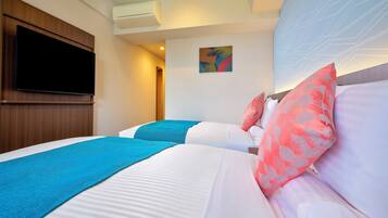 A hotel room with two beds, a flat-screen TV mounted on the wall, and an air conditioning unit.