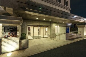 A modern building with a glass entrance, a brick facade, and a signboard.