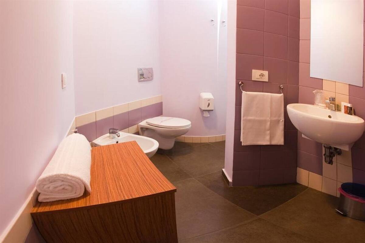 A bathroom with a wooden vanity, two toilets, a sink, and a mirror.