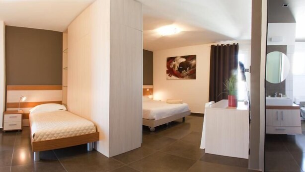 Quarto de hotel moderno com duas camas, banheiro com espelho e um quadro na parede.