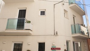 Um edifício de vários andares com varandas, uma entrada visível e uma placa indicando que é um hotel.