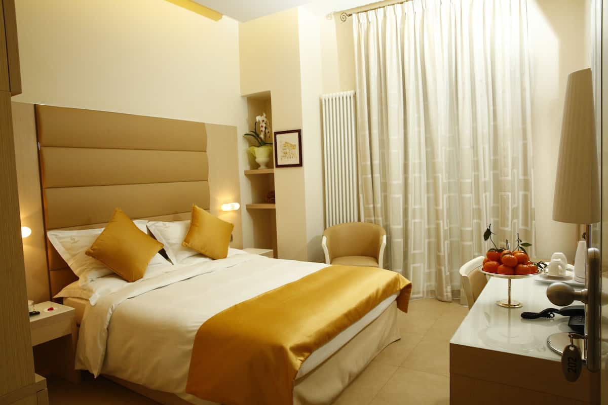 Una habitación de hotel con cama, mesita de noche, silla y una pequeña mesa con frutero.