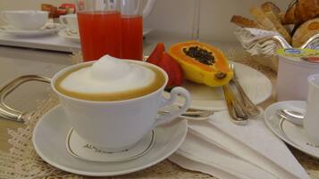 Una mesa con café, jugo de frutos rojos, mitad de papaya y pan.
