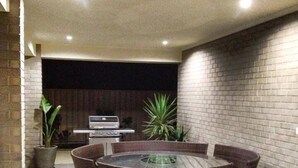 A circular dining area with a central table and chairs, surrounded by brick walls and potted plants.