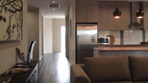 A modern kitchen with dark cabinets, a built-in oven, and pendant lighting.