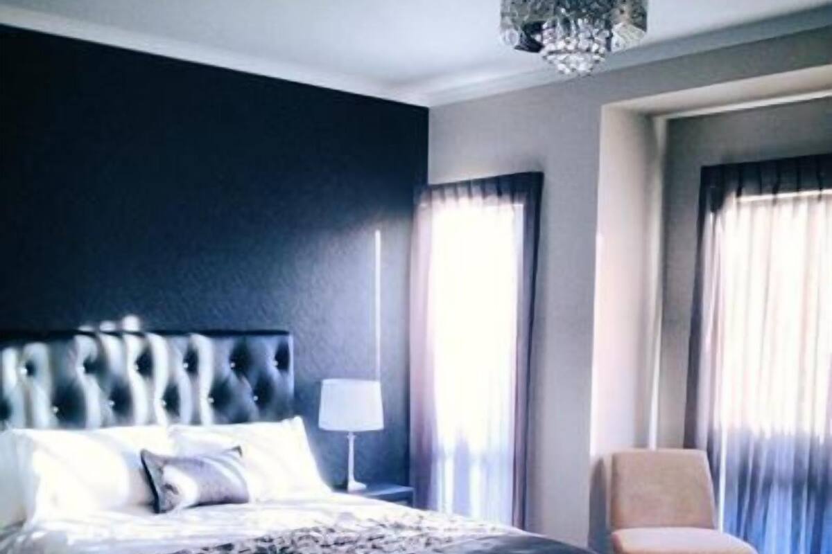 Una habitación de hotel con una cama grande, una silla, una lámpara y un candelabro.